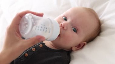 Anne bebeğini şişeyle besliyor.