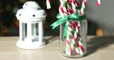 Mutlu Noeller ve mutlu yıllar. Kavanozlu şeker kamışı ve hafif ahşap masada fener, bulanık ışıklara karşı, yakın çekim. Kamera hareket ediyor
