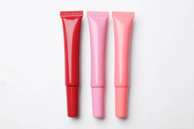 Beyaz arkaplanda farklı dudak parlatıcıları, düz yatış