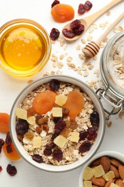 Tahıl yapıyorum. Yulaf gevreği, kurutulmuş meyve ve diğer malzemeler beyaz masada, düz yerde.