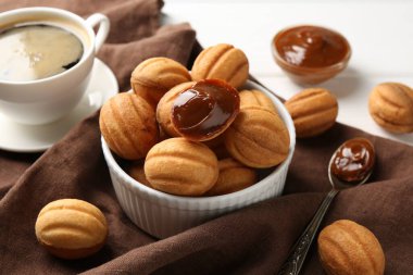 Lezzetli fındık şekilli kurabiyeler kaynatılmış konsantre süt ile beyaz masada servis edilir, yakın plan.