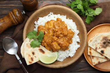 Pirinçli tavuk tikka masala, kişniş, kireç ve lavaş ahşap masada servis edilir.
