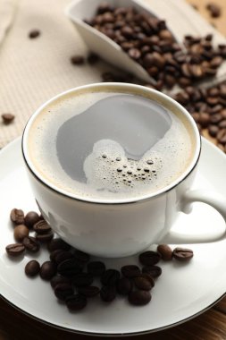 Aromatik kahve fincanda ve fasulye masada, yakın plan.