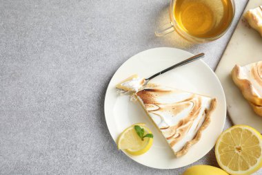 Slice of tasty lemon meringue tart with mint served on light grey table, flat lay. Space for text