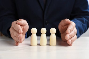 Beyaz tahta masada insan figürlerini koruyan adam, yakın plan.