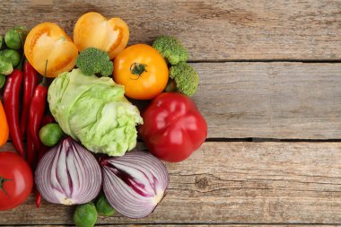 Different fresh raw vegetables on wooden table, flat lay. Space for text