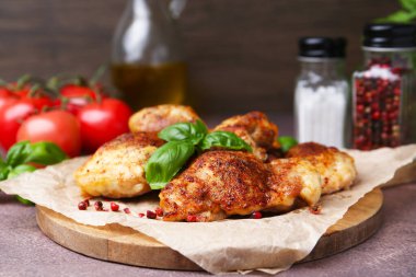 Tasty roasted chicken thighs with basil on wooden table, closeup
