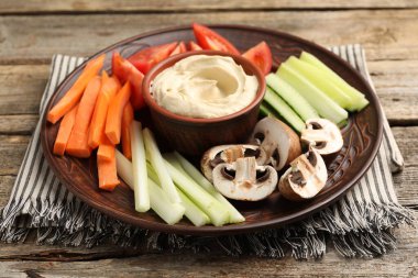 Farklı taze sebzeler ve ahşap masadaki sos, yakın plan.