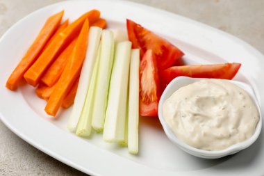 Açık gri masada farklı taze sebzeler ve sos, yakın plan.