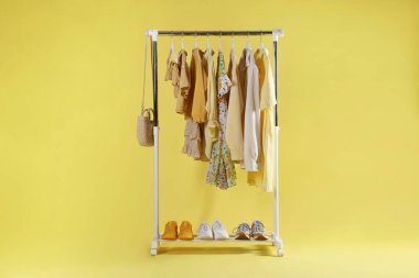 Sarı arka planda farklı şık kıyafetler, çanta ve ayakkabılar.