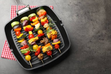 Grill pan with tasty vegetables on grey table, top view. Space for text