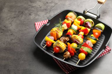 Grill pan with tasty vegetables on grey table, closeup. Space for text
