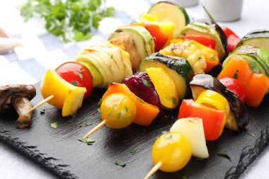 Skewers with tasty grilled vegetables on light table, closeup