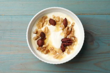 Delicious Greek yogurt with honey and nuts served on blue wooden table, top view