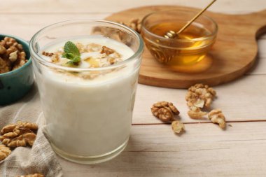 Delicious Greek yogurt with honey and walnuts served on white wooden table, closeup