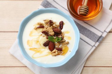 Delicious Greek yogurt with honey and nuts served on white wooden table, flat lay
