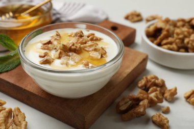 Delicious Greek yogurt with honey and walnuts served on white table, closeup