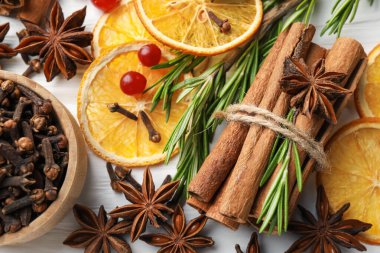Different spices, dry orange slices, cranberries and fresh rosemary for mulled wine on light table, flat lay