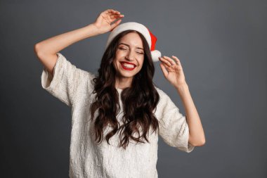 Noel Baba şapkalı güzel kadın gri arka planda eğleniyor. Noel partisi