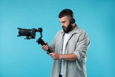 Açık mavi arkaplanda kameralı titreşim dengeleyici kullanan kameraman
