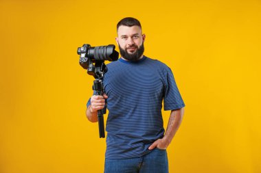 Sarı zemin üzerinde kamera olan titreşimli dengeleyici kullanan kameraman