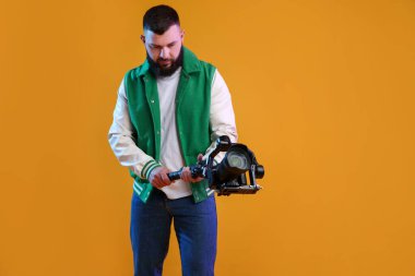 Kameraman sarı arka planda kameralı titreşimli dengeleyici kullanıyor. Metin için boşluk