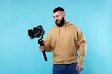 Açık mavi arkaplanda kameralı titreşim dengeleyici kullanan kameraman