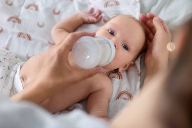 Anne bebeğini şişeyle besliyor.