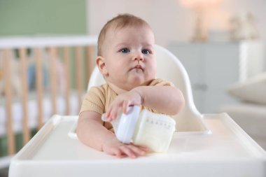 Evinde şezlongda yemek şişesi olan sevimli bir bebek.