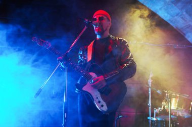 Sahnede elektro gitar çalan adam dumanlı, düşük açılı