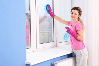 Camları paçavra ve deterjanla temizleyen kadın.