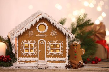 Güzel zencefilli kurabiye evi ve ahşap masanın üzerindeki Noel dekoru bulanık ışıklara karşı, yakın plan.