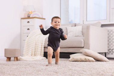 İlk adımlar. Evinde yerde yürüyen sevimli küçük bebek.