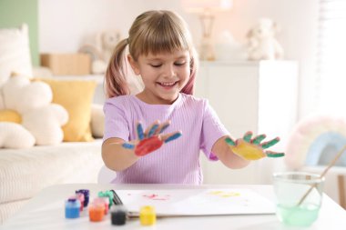Beyaz masalarda avuç içleri çizen sevimli küçük kız.