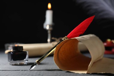 Eski kağıt parşömenler, dolmakalem, mürekkep hokkası ve yanan mum gri ahşap masa, seçici odak