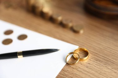 Nafaka. Kağıt, kalem, nişan yüzükleri ve paralar ahşap masaya, seçici odaklanma