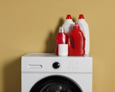 Modern çamaşır makinesi ve zeytin duvarının yanındaki deterjanlar.