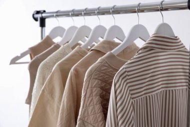 Farklı kadın kıyafetleri arka planda asılı, yakın plan.