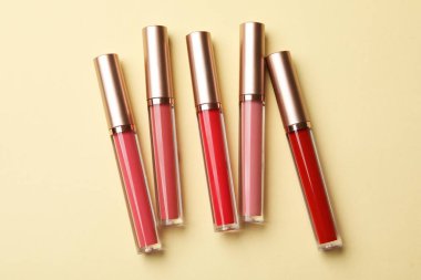 Bej arkaplanda farklı dudak parlatıcıları, düz yatış