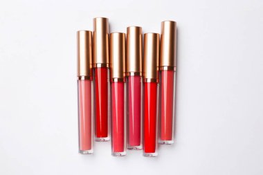 Beyaz arkaplanda farklı dudak parlatıcıları, düz yatış