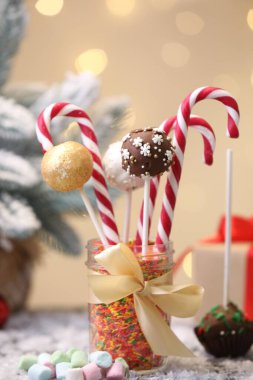 Kavanozda şeker kamışı, şekerleme ve şekerlemeler var. Masada bulanık ışıklara karşı, yakın plan.