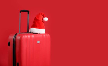 Kırmızı arka planda bavulda Noel Baba şapkası, mesaj için boşluk. Noel tatili