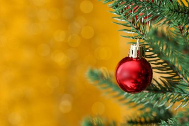 Beautiful ornament on Christmas tree against yellow background with blurred lights, closeup and space for text. Bokeh effect