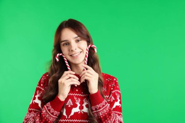 Yeşil arka planda şeker kamışlı genç kadın portresi, mesaj için yer. Mutlu Noeller ve mutlu yıllar.