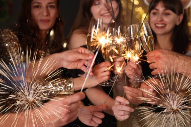 Köpüklü şarap ve maytap kadehleri olan arkadaşlar yeni yılı kutluyor, yakın plan.