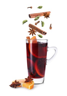 Sıcak şarap baharatları beyaz arka planda cam bardağa dökülüyor.