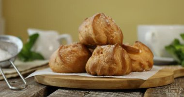 Tahta masadaki profiterollere nane ekleyen kadın, yakın plan.