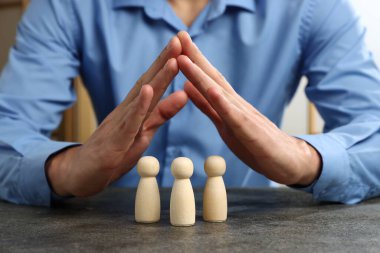 Gri masada insan figürlerini koruyan adam, yakın plan.