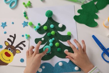 Küçük çocuk Noel kartpostalı hazırlıyor. Çocuk el yapımı.