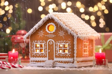 Güzel zencefilli kurabiye evi ve bulanık ışıklara karşı yanan mumlar, yakın plan. Noel hediyesi